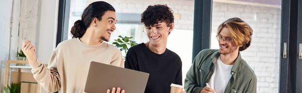 excited young men engaged in a lively discussion over a laptop at a coworking space, startup banner - Photo, Image