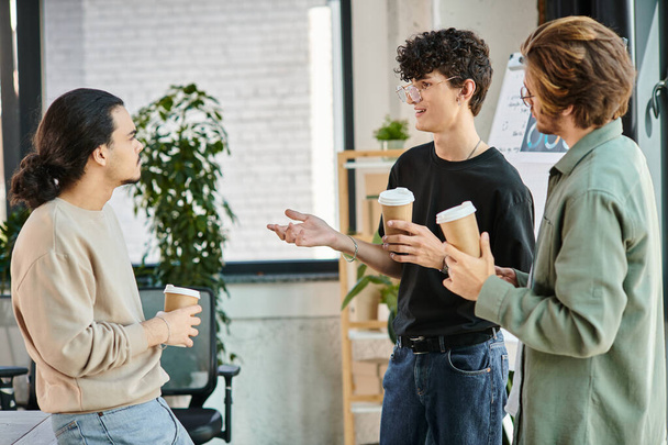 молодые коллеги в возрасте 20 лет делятся идеями за чашкой кофе в современном офисе стартапа, командная работа - Фото, изображение