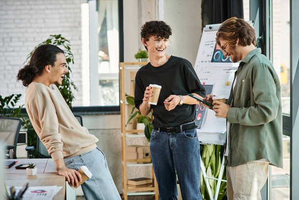 jeunes collègues dans la vingtaine partageant des idées et riant autour d'un café dans un bureau moderne, équipe de démarrage - Photo, image