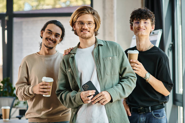 Drie jonge mannen in de 20 met koffie in een vriendelijke kantoorsfeer, professionele headshot - Foto, afbeelding