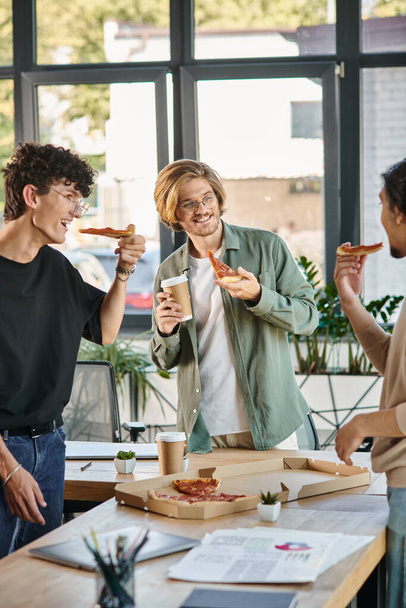 gelukkige mannen genieten van een pizza lunch pauze in een vriendelijke en ontspannen kantoorsfeer, startup team - Foto, afbeelding
