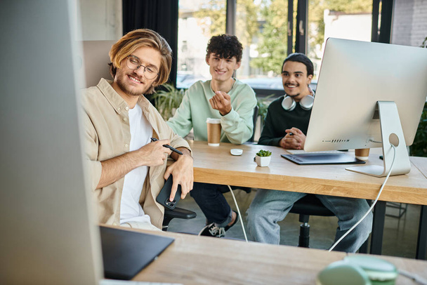 szczęśliwy zespół kreatywny skupiony na pracy postprodukcyjnej patrząc na monitor w biurze, mężczyźni w wieku 20 lat - Zdjęcie, obraz