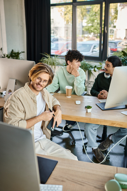 szczęśliwy zespół kreatywny intensywnie skupiony na pracy postprodukcyjnej w nowoczesnym biurze, mężczyźni w wieku 20 lat - Zdjęcie, obraz