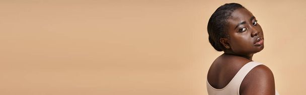 jeune femme afro-américaine taille plus en sous-vêtements beige posant sur fond assorti, bannière - Photo, image