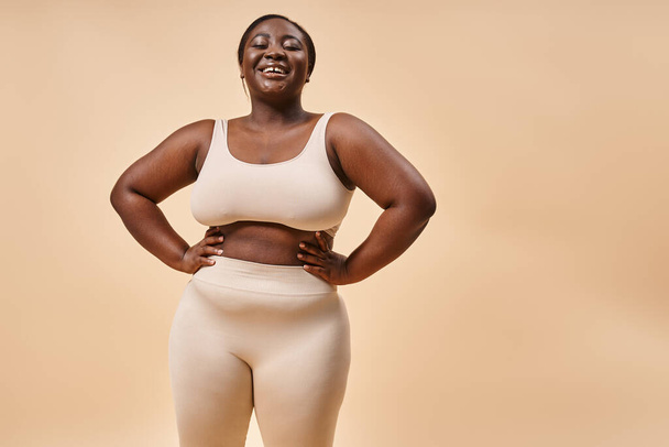 gelukkig plus size vrouw in ondergoed poseren met handen op heupen, lichaam positieve en vrouwelijke empowerment - Foto, afbeelding
