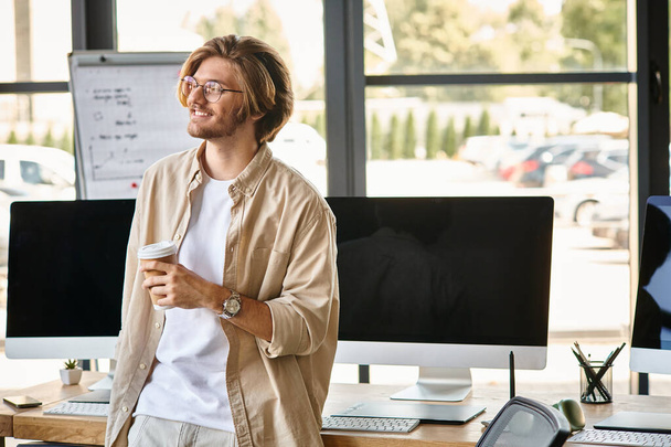 Homme souriant avec des lunettes tenant du café dans une configuration de bureau moderne, retouche de l'équipe de post-production - Photo, image