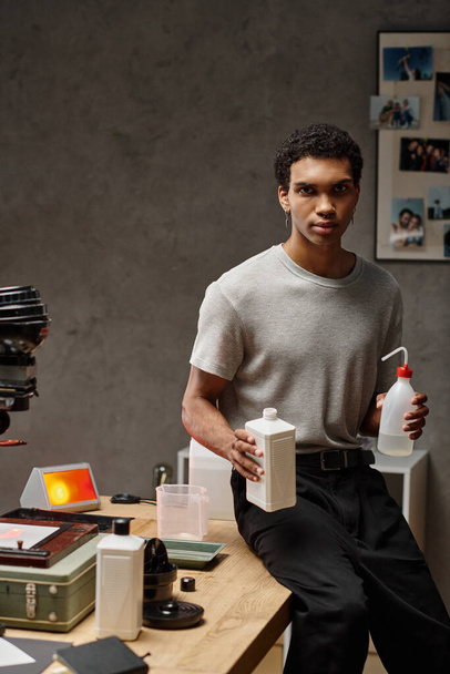 hombre afroamericano enfocado midiendo cuidadosamente productos químicos de película fotográfica en un cuarto oscuro bien organizado - Foto, Imagen