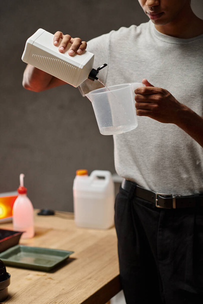 vágás afro-amerikai férfi öntés kémiai oldat mérőkupa, film fejlesztés - Fotó, kép