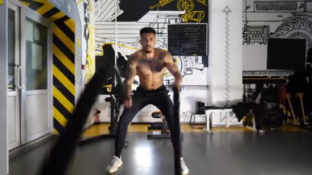 Strong african athlete training with battle ropes in fitness centre. Muscular afro american sportsman with tattoos exercising hard at modern gym. Concept of healthy and active lifestyle. Slow motion. - Footage, Video