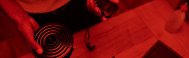 Kırmızı ışıklı karanlık odada kırpılmış fotoğrafçı, zamanlayıcı ile siyah adam, film geliştirme afişi - Fotoğraf, Görsel