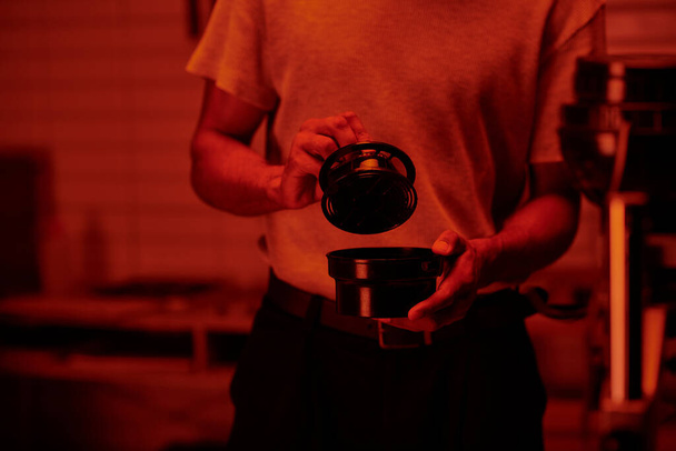 bijgesneden opname van fotograaf met filmbus en het ontwikkelen van foto 's in donkere kamer met rood licht - Foto, afbeelding