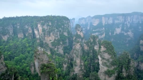 Kína - Zhangjiajie kő Várnegyedbe oszlopok szikla hegység köd felhők, Wulingyuan, Hunan, Kína. A kamerát pan - Felvétel, videó