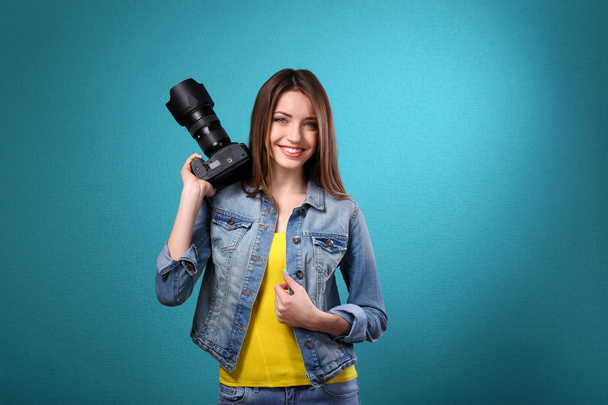 Young female photographer taking photos on blue background - Φωτογραφία, εικόνα