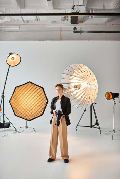 attractive female photographer in everyday outfit looking at camera surrounded by her equipment - Photo, Image