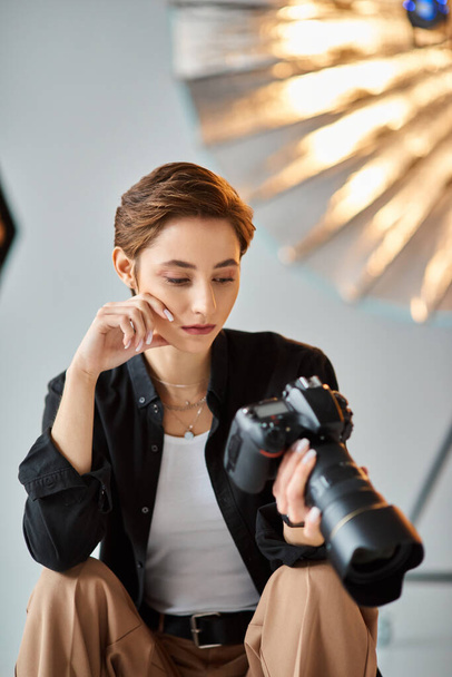 giovane bella fotografa donna in abbigliamento casual guardando le foto sulla sua macchina fotografica in studio - Foto, immagini