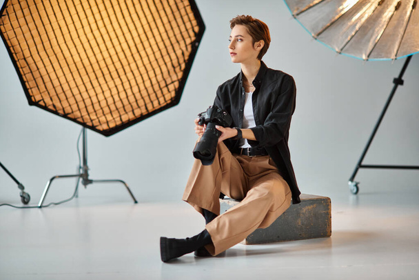 attractive young female photographer in everyday attire posing in her studio and looking away - 写真・画像