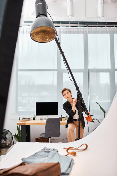 encantador fotógrafo feminino de cabelos curtos em traje casual trabalhando com seu equipamento no estúdio - Foto, Imagem