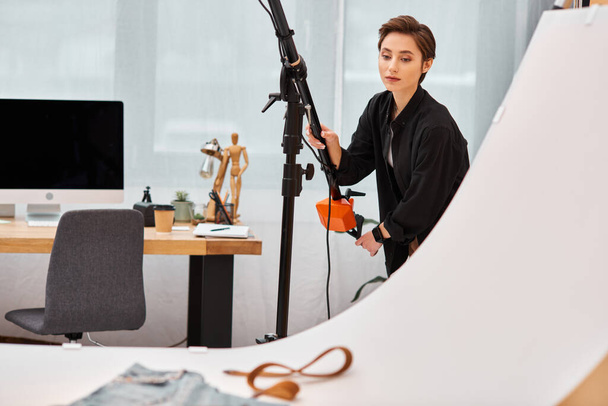 εμφανίσιμη νεαρή φωτογράφος με casual ρούχα που δουλεύει με τον εξοπλισμό της στο studio - Φωτογραφία, εικόνα
