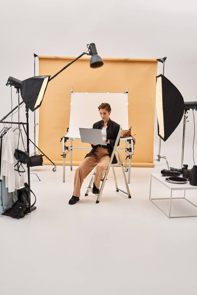 beautiful short haired photographer sitting and retouching photos in her studio using her laptop - Photo, Image