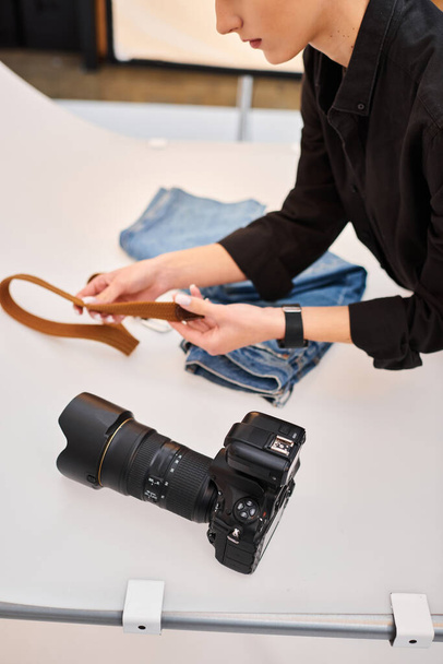 vista recortada de la joven fotógrafa talentosa preparándose para hacer fotos de objetos de mezclilla - Foto, imagen