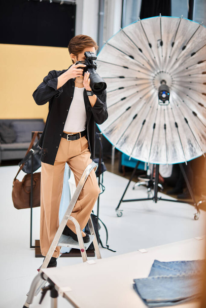goed uitziende jonge vrouw in casual kleding het nemen van foto 's met haar moderne camera in haar studio - Foto, afbeelding