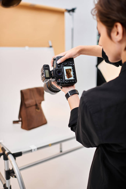彼女のスタジオで茶色の革のバックパックの写真を撮る魅力的な短髪の女性の写真家 - 写真・画像