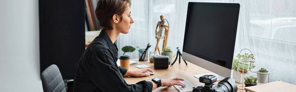 professionele vrouwelijke fotografe in casual wear retoucheren foto 's op de computer in haar studio, banner - Foto, afbeelding