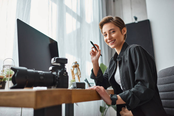 vrolijke vrouw werken met tekening tablet en haar camera in de voorkant van de computer en vrolijk glimlachen - Foto, afbeelding