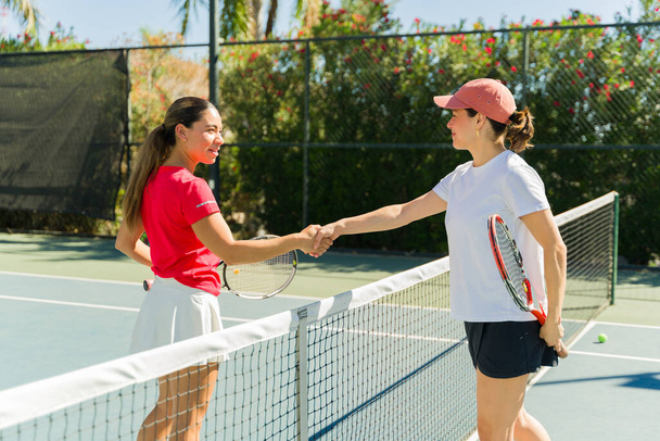 Aktive schöne Frauen schütteln Hände und feiern nach einem guten Tennismatch auf dem Tennisplatz im Freien - Foto, Bild