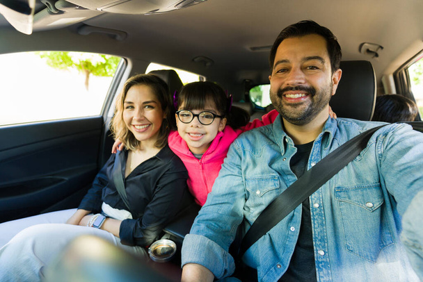 Persoonlijk perspectief van een gelukkige vader het nemen van een selfie met zijn vrolijke familie tijdens het rijden op een road trip - Foto, afbeelding