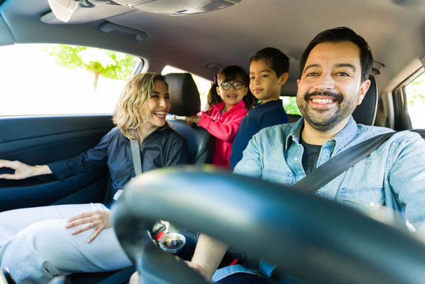 Beautiful happy caucasian family smiling going on a fun road trip and driving the car having fun together - Photo, Image
