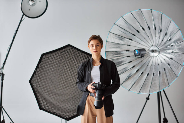 молодая красивая женщина-фотограф в повседневной одежде смотрит в камеру в своей студии - Фото, изображение