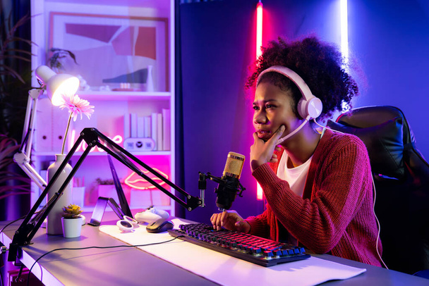 African American girl streamer disappointed playing online fighting with Esport skilled team wearing headphones in neon room. Talking other players planing strategies to win competitors. Tastemaker. - Photo, Image