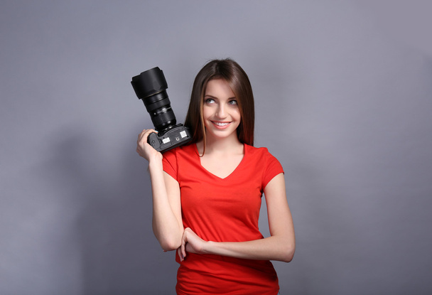 Young female photographer taking photos on grey background - Foto, Imagem