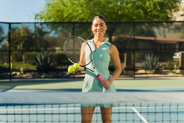 Smiling beautiful mexican woman and tennis player looking happy while practicing tennis sports  - Photo, Image