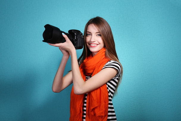 Young female photographer taking photos on blue background - Foto, Imagen