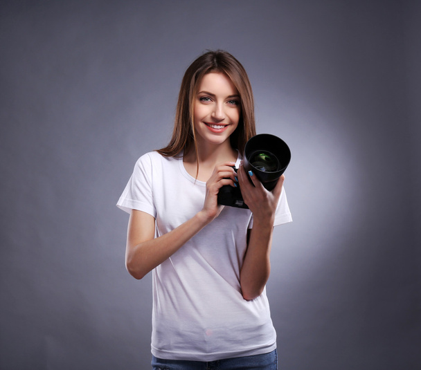 Young female photographer taking photos on grey background - Photo, image