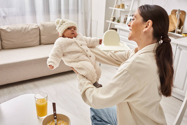 happy beautiful woman in homewear holding her cute baby boy during breakfast, modern parenting - Photo, Image