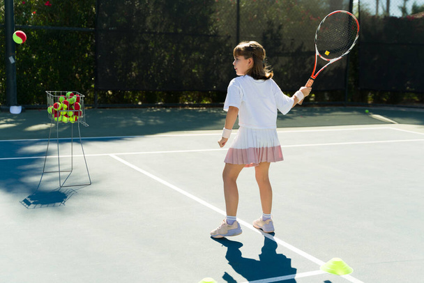 belle adorable caucasien adolescent fille pratiquant son coup droit et le revers tout à l'école de tennis  - Photo, image