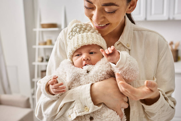 привлекательная заботливая мать в удобной домашней одежде с теплым уходом за малышом, современное воспитание - Фото, изображение