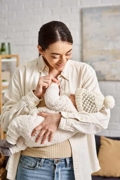 attractive cheerful mother in homewear holding lovingly her newborn baby boy, modern parenting - 写真・画像