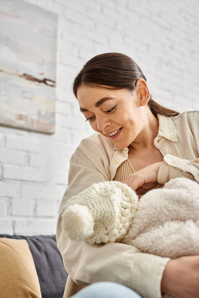 bien parecido cuidado alegre madre en acogedora ropa de casa amamantando a su hijo recién nacido, crianza moderna - Foto, imagen