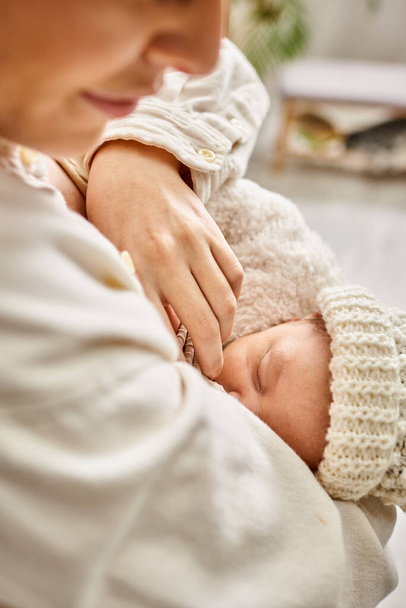 ansprechende fürsorgliche freudige Mutter in gemütlicher Hauskleidung, die ihr neugeborenes Kind stillt, moderne Elternschaft - Foto, Bild