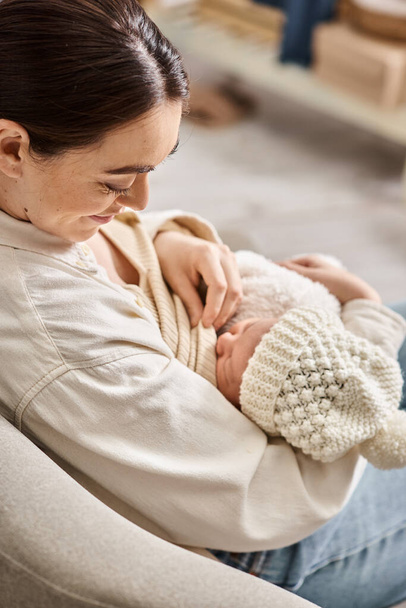 beautiful woman in cozy casual attire breastfeeding her cute newborn child, modern parenting - Photo, Image