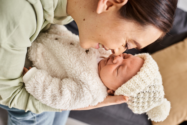 cheerful good looking woman in cozy homewear holding her adorable newborn baby boy, modern parenting - Photo, Image