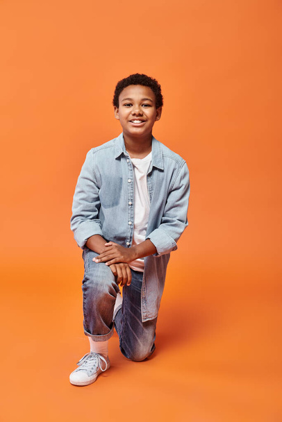 陽気なアフリカ系アメリカ人の男の子は,片膝に立って喜んでカメラで笑顔で - 写真・画像