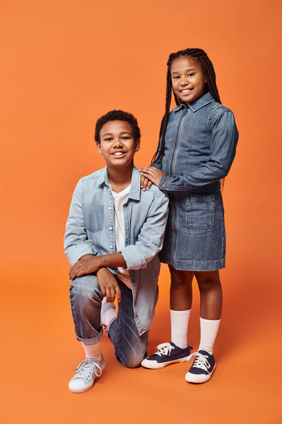happy preteen african american friends in casual outfits posing together on orange backdrop - Photo, Image