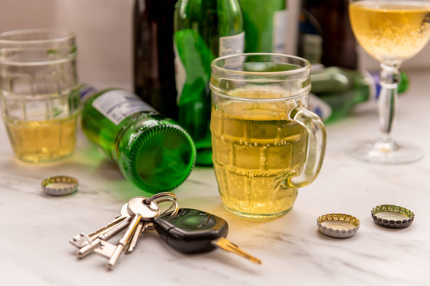 Alkollü içki ve şişelerle dolu bir masanın üzerinde bir takım araba anahtarı. İçkili sürüş. - Fotoğraf, Görsel