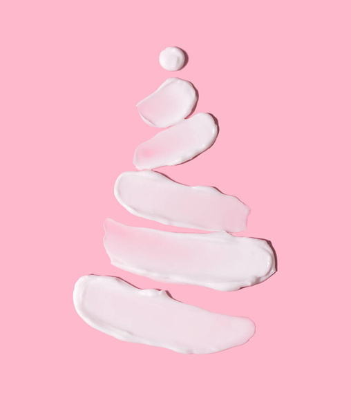 O conceito de uma árvore de Natal na forma de traços cosméticos em um fundo rosa. Hidratação da pele no inverno. - Foto, Imagem