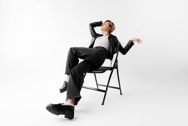 Eine trendige Frau räkelt sich im Stuhl und schaukelt ein monochromes Outfit mit unbeschwerter Attitüde - Foto, Bild